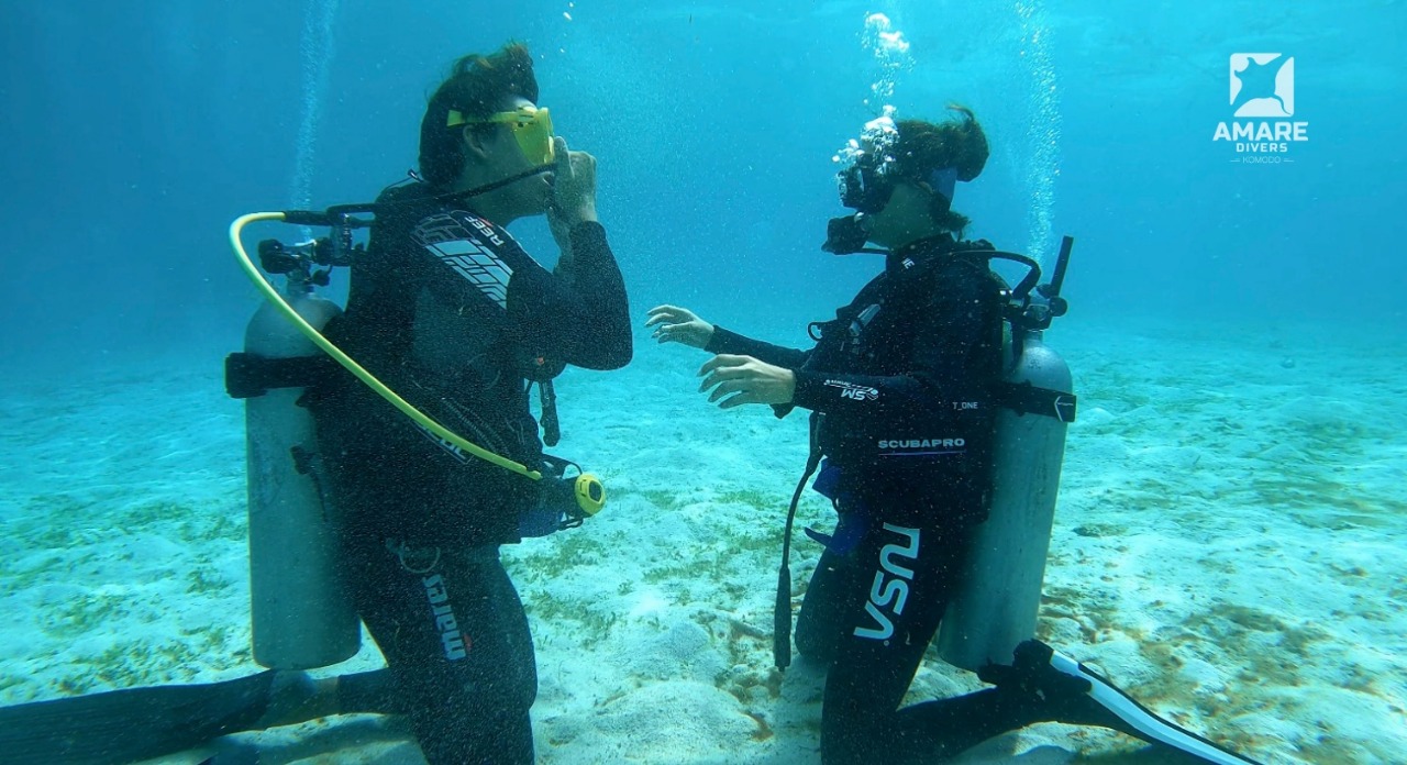 Instructor teaching basic scuba skills to a new diver in shallow water during SSI Open Water training in Komodo